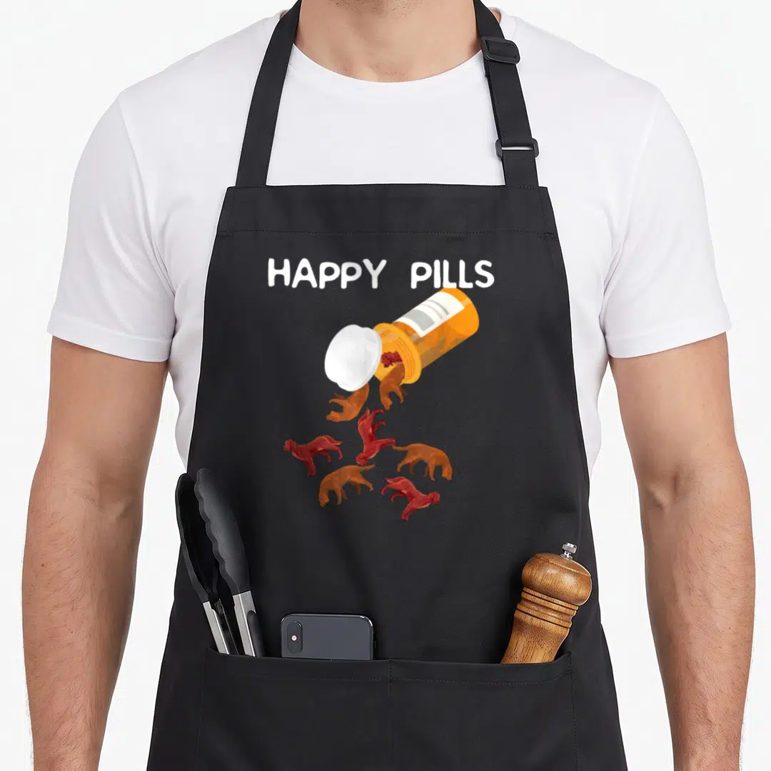 Setter irish aprons - HAPPY PILLS text above orange bottle spilling small reddish-brown dogs — shown on a black cotton canvas apron against a white background