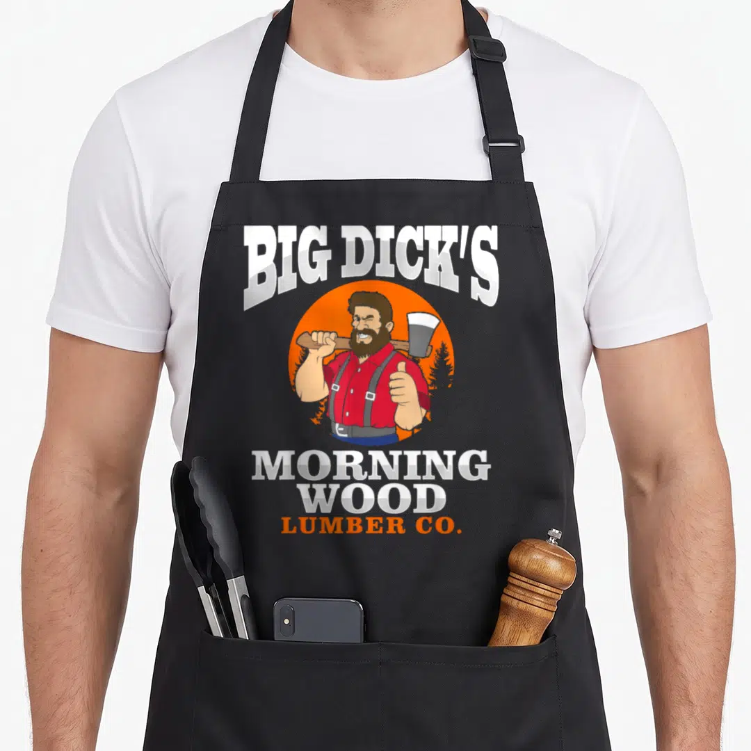 Carpenter wood apron - Cartoon lumberjack in orange circle holding axe with Big Dick's Morning Wood Lumber Co text — shown on a black cotton canvas apron against a white background