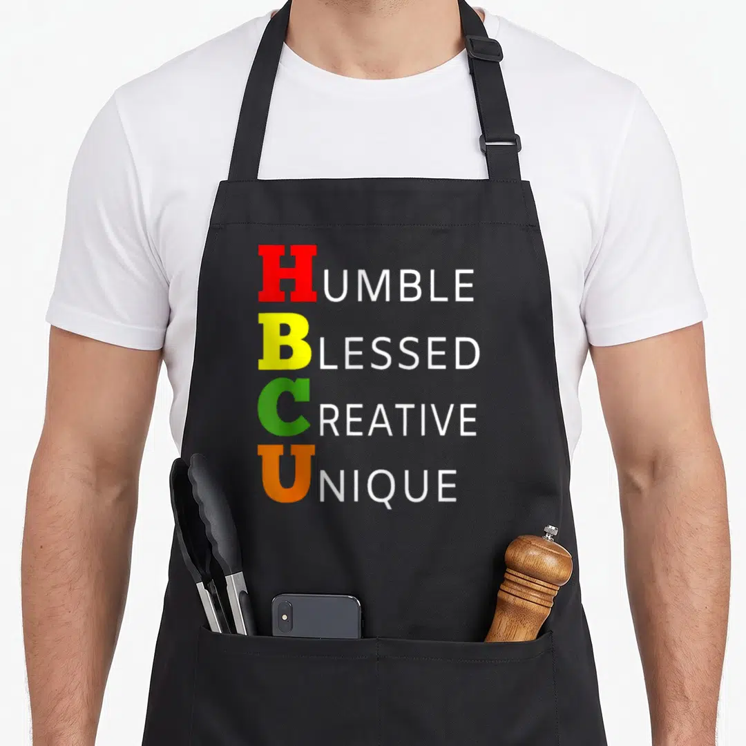 Historically college student aprons - Stacked text Humble Blessed Creative Unique with colored HBCU initials — shown on a black cotton canvas apron against a white background