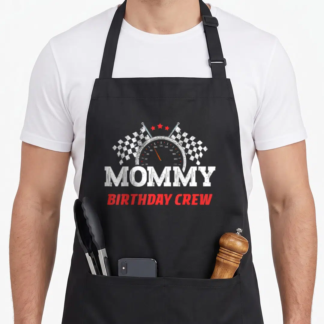 Driver crew aprons - Speedometer graphic with checkered flags and MOMMY BIRTHDAY CREW text in distressed style — shown on a black cotton canvas apron against a white background