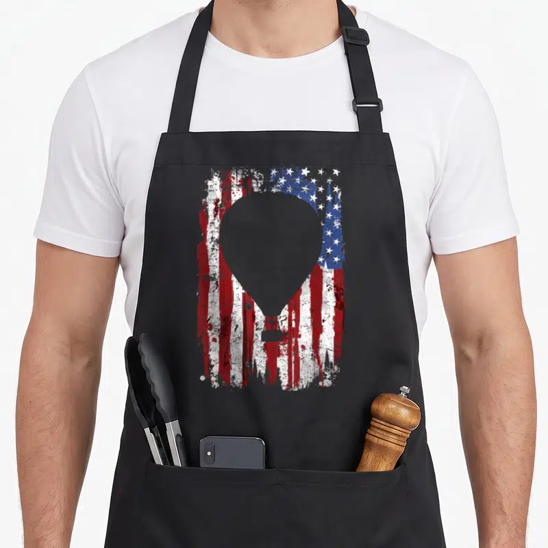 Flag balloon apron - Grey hot air balloon silhouette over distressed red white and blue American flag pattern — shown on a black cotton canvas apron against a white background