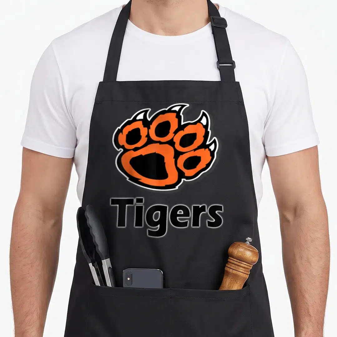 Paw school apron - Orange and black paw print logo above the word Tigers with white outline — shown on a black cotton canvas apron against a white background