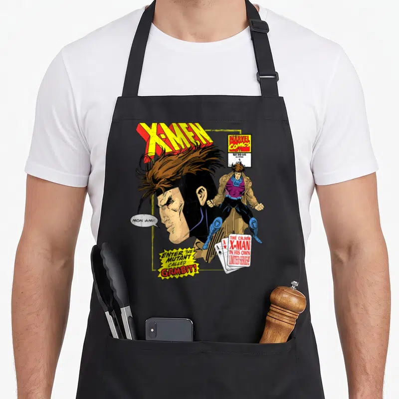 Remy cajun aprons - Vintage comic cover art of Gambit with playing cards, speech bubble, and X-Men logo in yellow — shown on a black cotton canvas apron against a white background