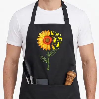 Save animal rescue apron - Sunflower with cat dog silhouettes and vertical Rescue Save Love text — shown on a black cotton canvas apron against a white background