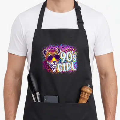 90s leopard aprons - Cartoon leopard with sunglasses and 90s GIRL text on rainbow splash background — shown on a black cotton canvas apron against a white background
