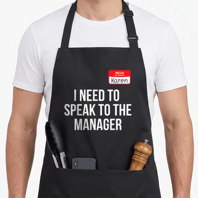 Speak manager halloween apron - Red name tag reading Hello my name is Karen above three lines of white text I need — shown on a black cotton canvas apron against a white background