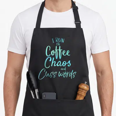 Chao coffee apron - Teal and light blue stacked typography reading I Run on Coffee Chaos and Cuss Words — shown on a black cotton canvas apron against a white background