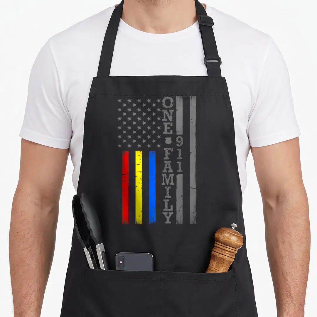 Fire service apron - Distressed grey flag with red yellow blue stripes and vertical One Big Family 911 text — shown on a black cotton canvas apron against a white background