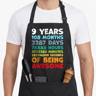 Bday dad and son aprons - Stacked colorful text listing 9 years, months, days, hours, minutes, seconds of being awesome — shown on a black cotton canvas apron against a white background