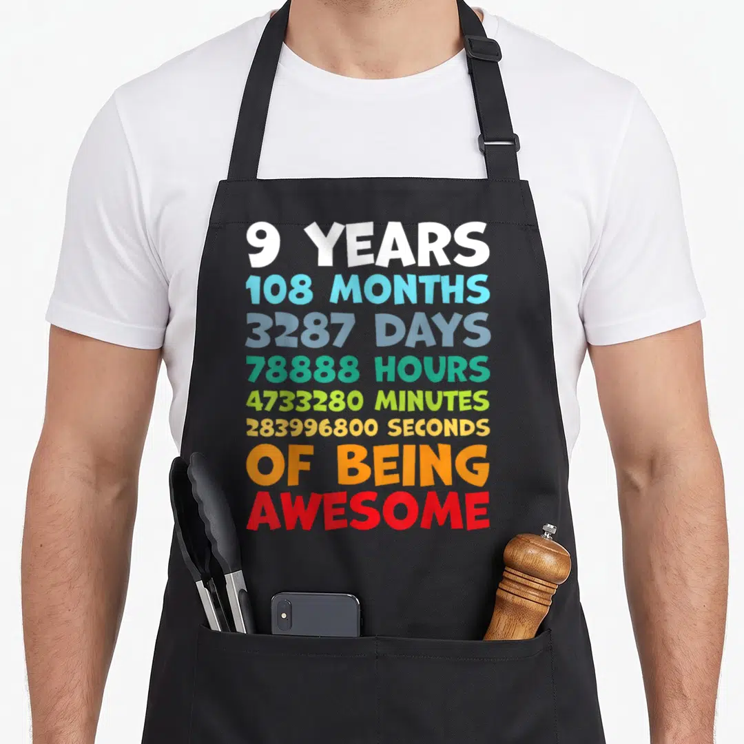 Bday dad and son aprons - Stacked colorful text listing 9 years, months, days, hours, minutes, seconds of being awesome — shown on a black cotton canvas apron against a white background