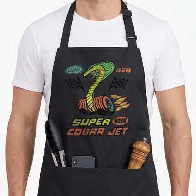 Ford f150 apron - Cobra rises from two tires with fire, checkered flags, and stacked Super Cobra Jet text in retro — shown on a black cotton canvas apron against a white background