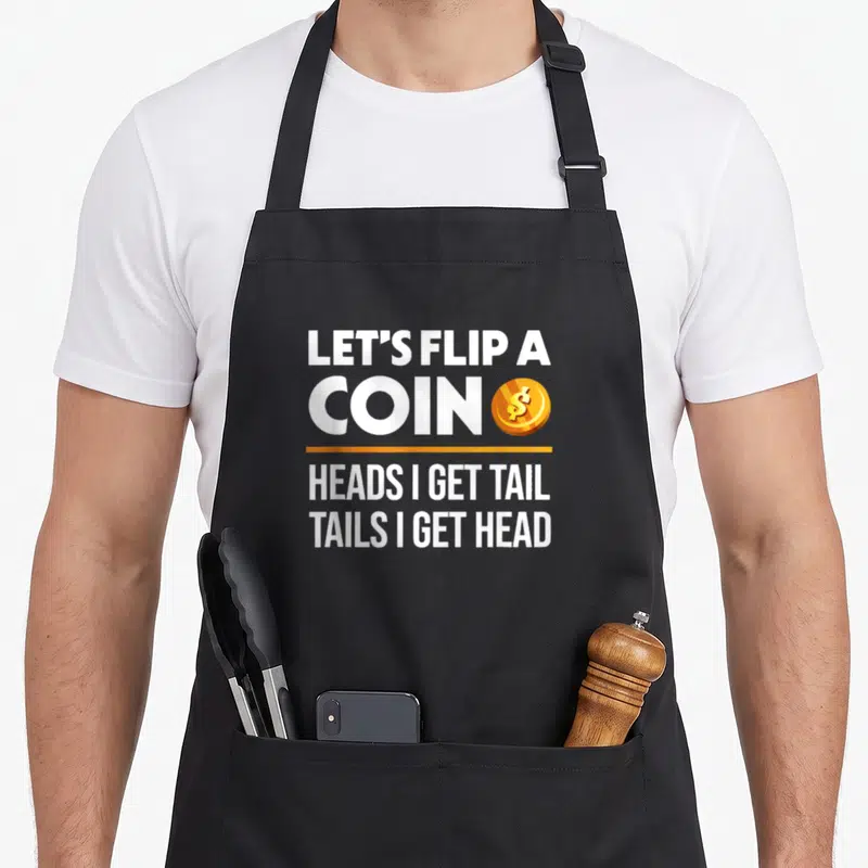 Flip dirty joke aprons - White stacked text reading Let's Flip A Coin Heads I Get Tail Tails I Get Head next to a gold — shown on a black cotton canvas apron against a white background