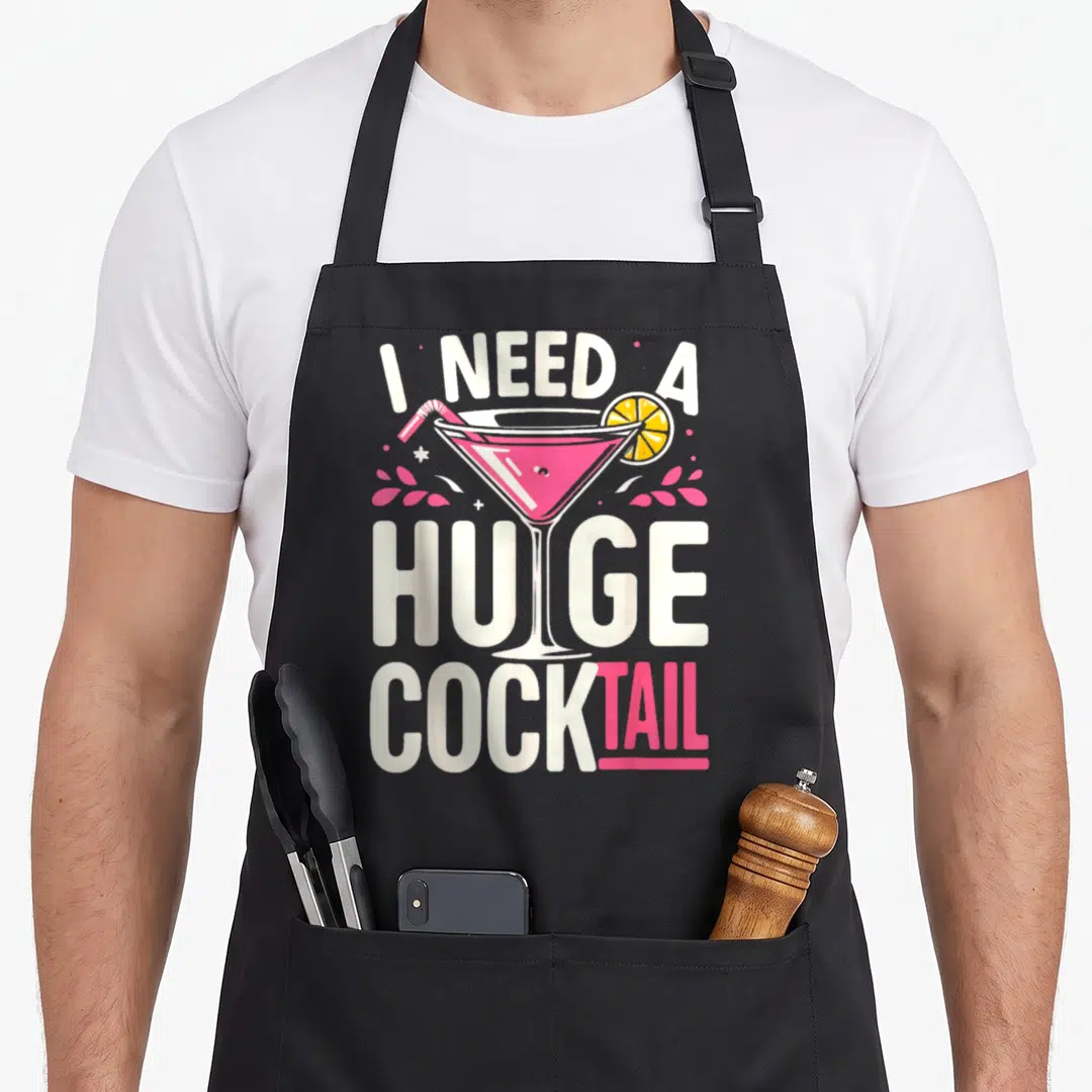 Huge cocktail apron - Retro pink martini glass overlapping white text reading I NEED A HUGE COCKTAIL — shown on a black cotton canvas apron against a white background