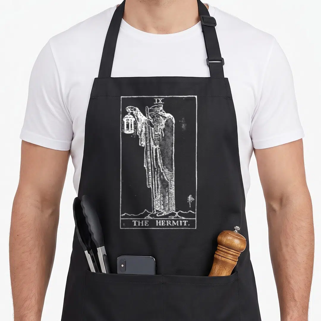 Hermite tarot apron - White line art of The Hermit tarot figure holding a lantern inside a rectangular border — shown on a black cotton canvas apron against a white background