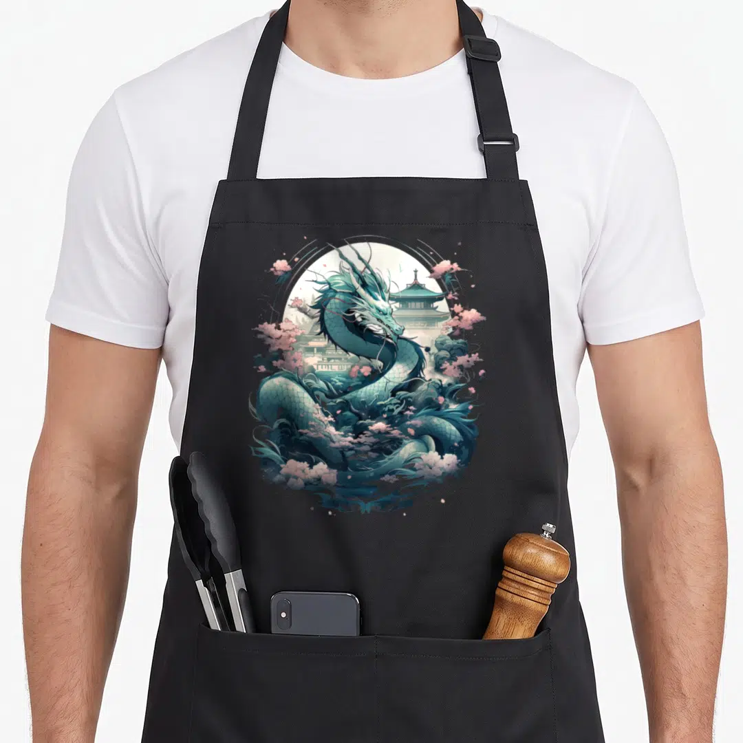 Tattoo japan apron - Coiled teal dragon with pink blossoms and pagoda in cartoon style — shown on a black cotton canvas apron against a white background