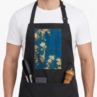 Goldfinch cherry apron - Realistic bird perched upside down on cherry blossoms with calligraphy on blue background — shown on a black cotton canvas apron against a white background
