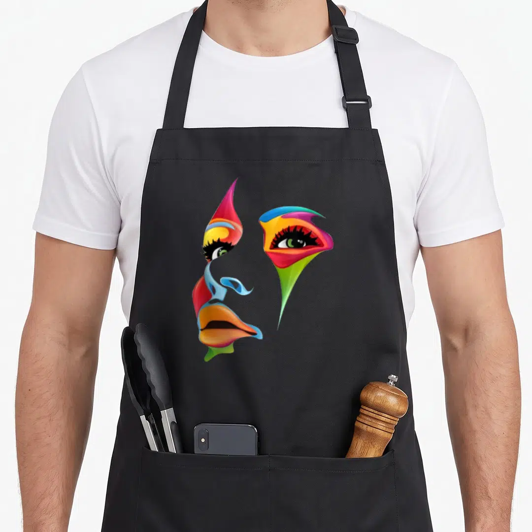 Abstract colorful apron - Scattered cartoon face with red blue yellow green orange eyes lips nose no outline — shown on a black cotton canvas apron against a white background