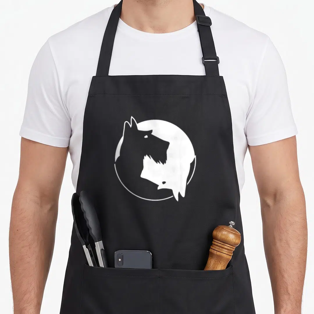 Yang dog dad apron - White circle containing negative space Scottish Terrier head silhouette on black fabric — shown on a black cotton canvas apron against a white background