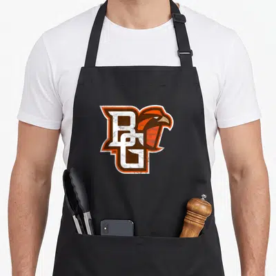 Distressed falcon apron - Distressed BG monogram with falcon head in orange brown and white outline — shown on a black cotton canvas apron against a white background