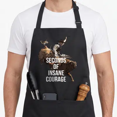 Bull taffy apron - 8 Seconds of Insane Courage text over a bull rider silhouette — shown on a black cotton canvas apron against a white background
