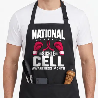 Sickle cell ribbon apron - Stacked white text reading National Sickle Cell Awareness Month with red boxing gloves — shown on a black cotton canvas apron against a white background