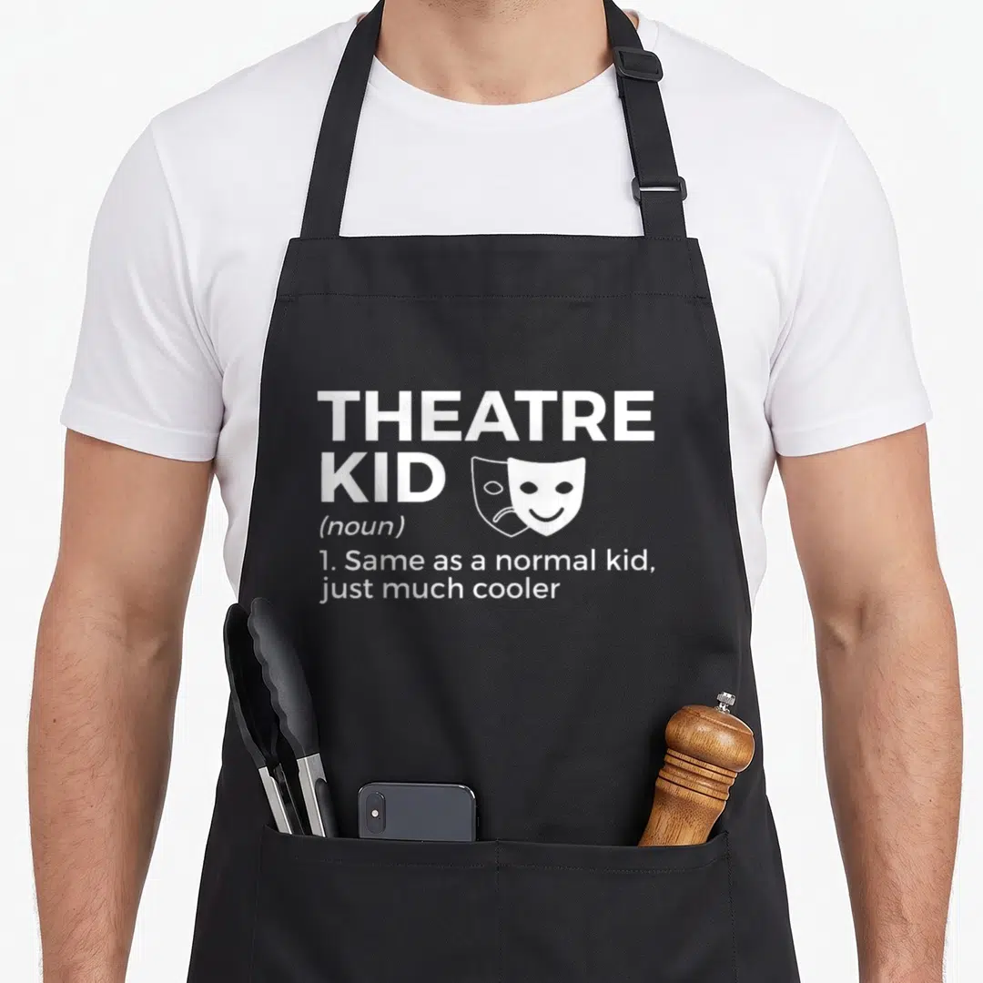 Definition theatre apron - White text reading Theatre Kid definition next to two overlapping comedy and tragedy masks — shown on a black cotton canvas apron against a white background