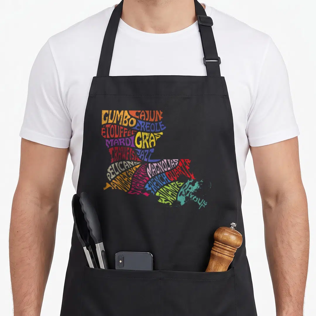 Louisiana mardi gras aprons - Typographic Louisiana state map formed by words like Gumbo, Jazz, Pelicans, and Magnolias — shown on a black cotton canvas apron against a white background
