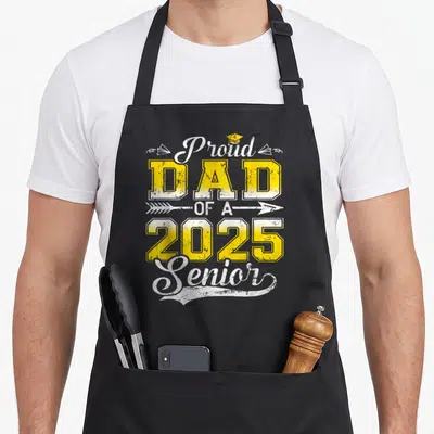Proud graduate senior dad apron - Stacked yellow and white text reading Proud DAD OF A 2025 Senior with cap and planes — shown on a black cotton canvas apron against a white background