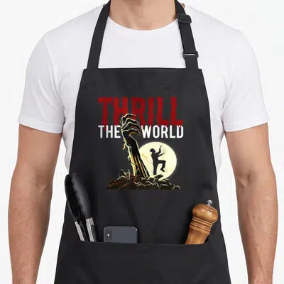 Ttw thrill apron - Zombie hand reaching from rocks under dripping red THRILL text with dancing moon silhouette — shown on a black cotton canvas apron against a white background