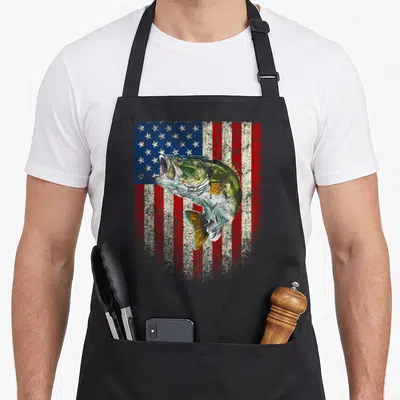 Onback american flag apron - Distressed bass fish leaping over red white and blue stars and stripes background — shown on a black cotton canvas apron against a white background