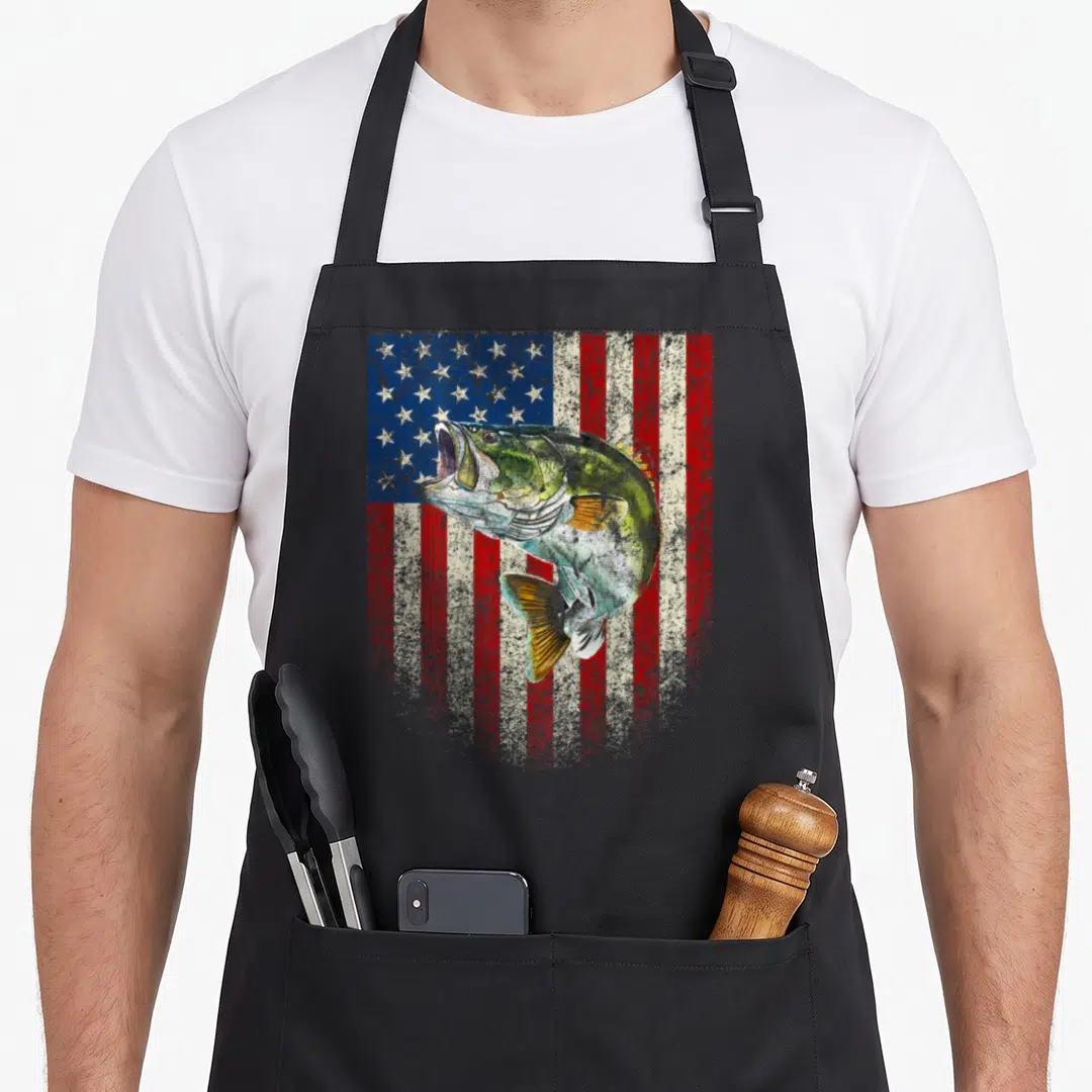 Onback american flag apron - Distressed bass fish leaping over red white and blue stars and stripes background — shown on a black cotton canvas apron against a white background