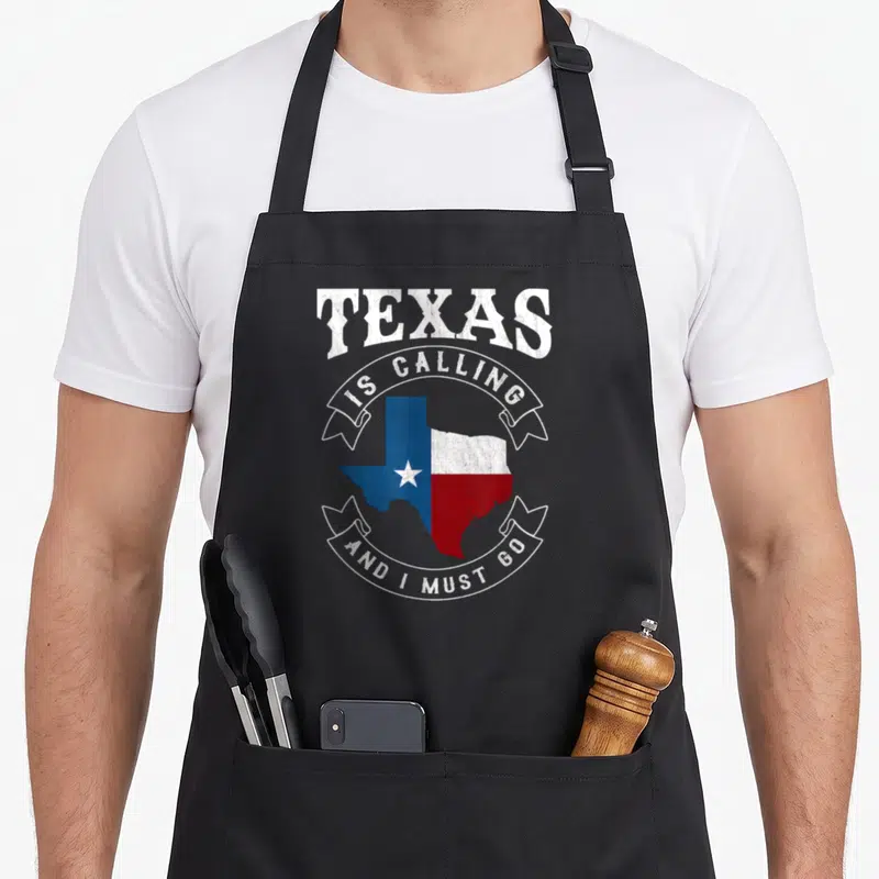 Calling must texas apron - Retro Texas map in blue white and red with arched text and two white ribbons containing — shown on a black cotton canvas apron against a white background