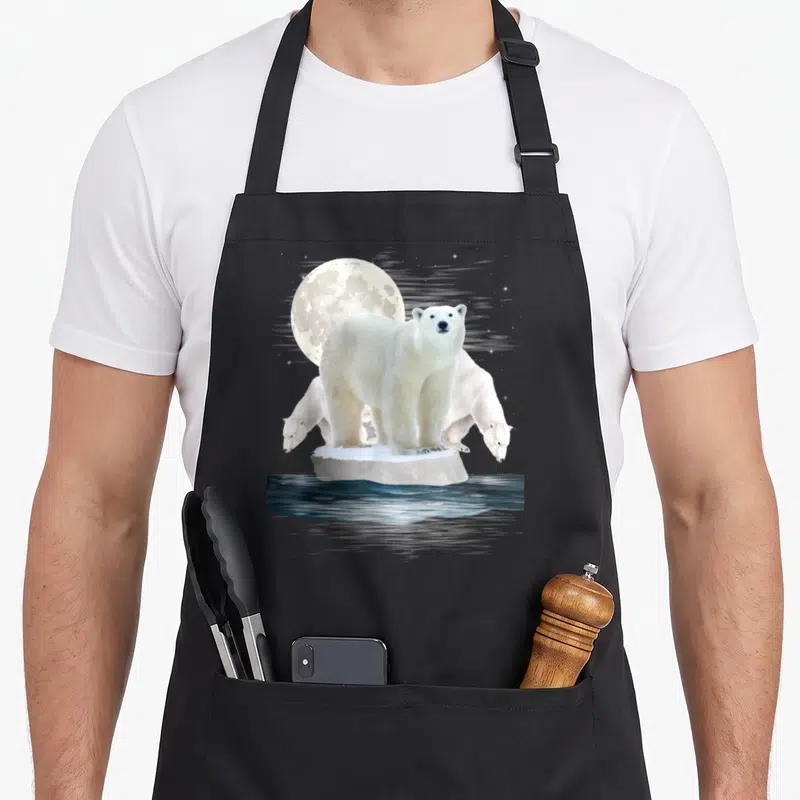 Zoo bear apron - Polar bear standing on ice floe with two others under a moon over dark water — shown on a black cotton canvas apron against a white background