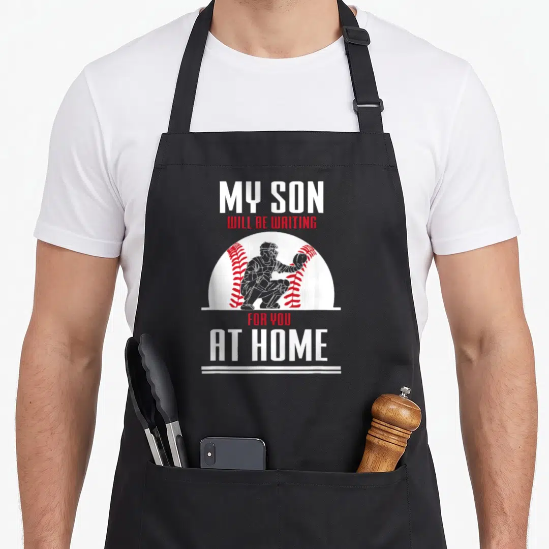 Baseball sports team aprons - Catcher graphic with My Son Will Be Waiting For You At Home text in white and red — shown on a black cotton canvas apron against a white background
