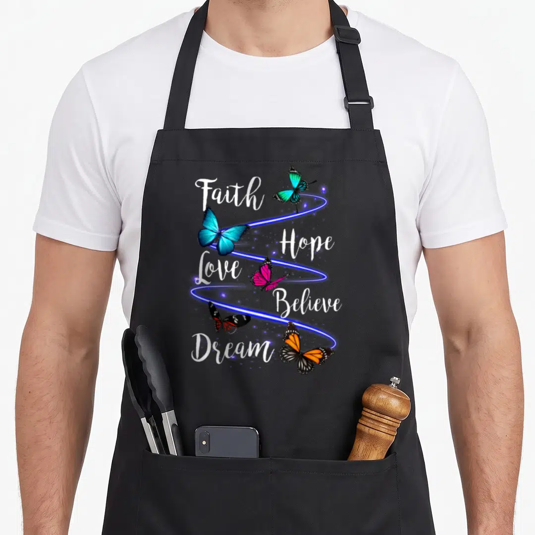 Butterfly christian apron - Faith Hope Love Believe Dream text with blue pink orange butterflies and blue swirls — shown on a black cotton canvas apron against a white background
