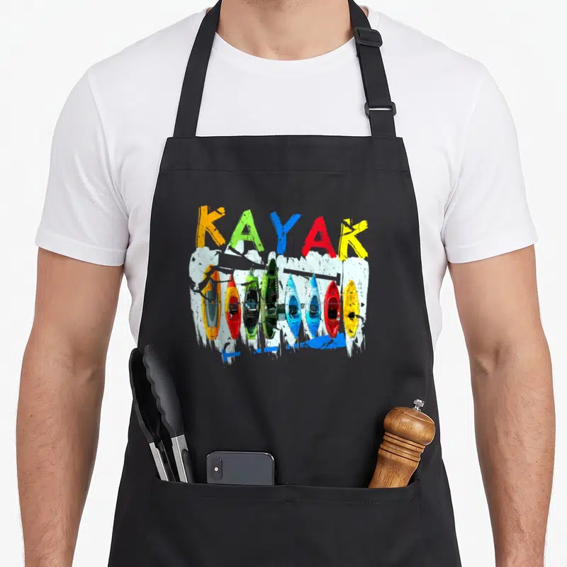 Kayaking canoeing apron - KAYAK text in orange green blue red yellow above seven top-down kayaks on white splash — shown on a black cotton canvas apron against a white background