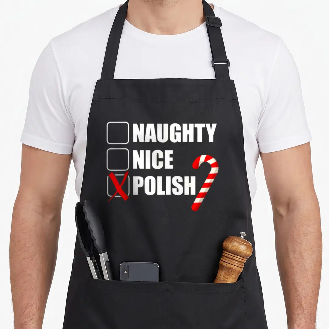 Merry polish kitchen aprons - White and red checklist with NAUGHTY NICE POLISH text and checked box next to candy cane — shown on a black cotton canvas apron against a white background