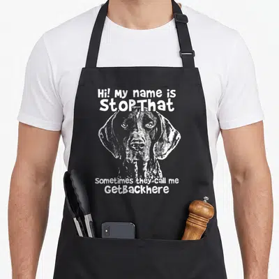 Stopthat pointer apron - White line art dog head centered between text reading Hi My Name Is StopThat and Sometimes — shown on a black cotton canvas apron against a white background