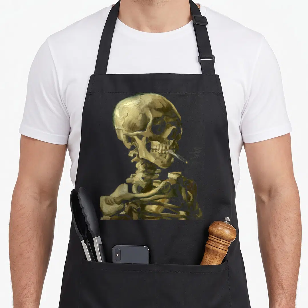 Vincent smoking apron - Realistic golden skeleton with cigarette in mouth, brown and gold tones — shown on a black cotton canvas apron against a white background