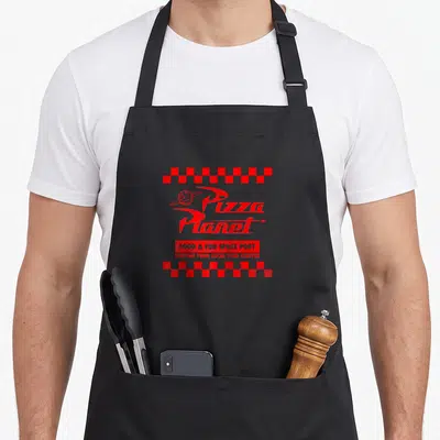 Baseball pizza planet apron - Red Pizza Planet logo framed by two checkered rows with Food Fun Space Port text — shown on a black cotton canvas apron against a white background