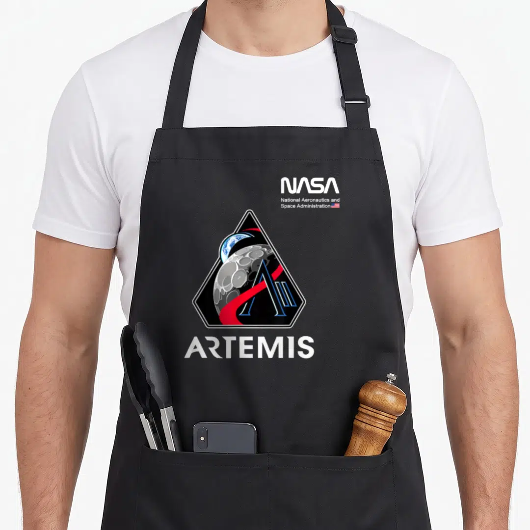 Artemis nasa apron - Triangular emblem with moon earth and stylized A above white ARTEMIS text and NASA logo — shown on a black cotton canvas apron against a white background