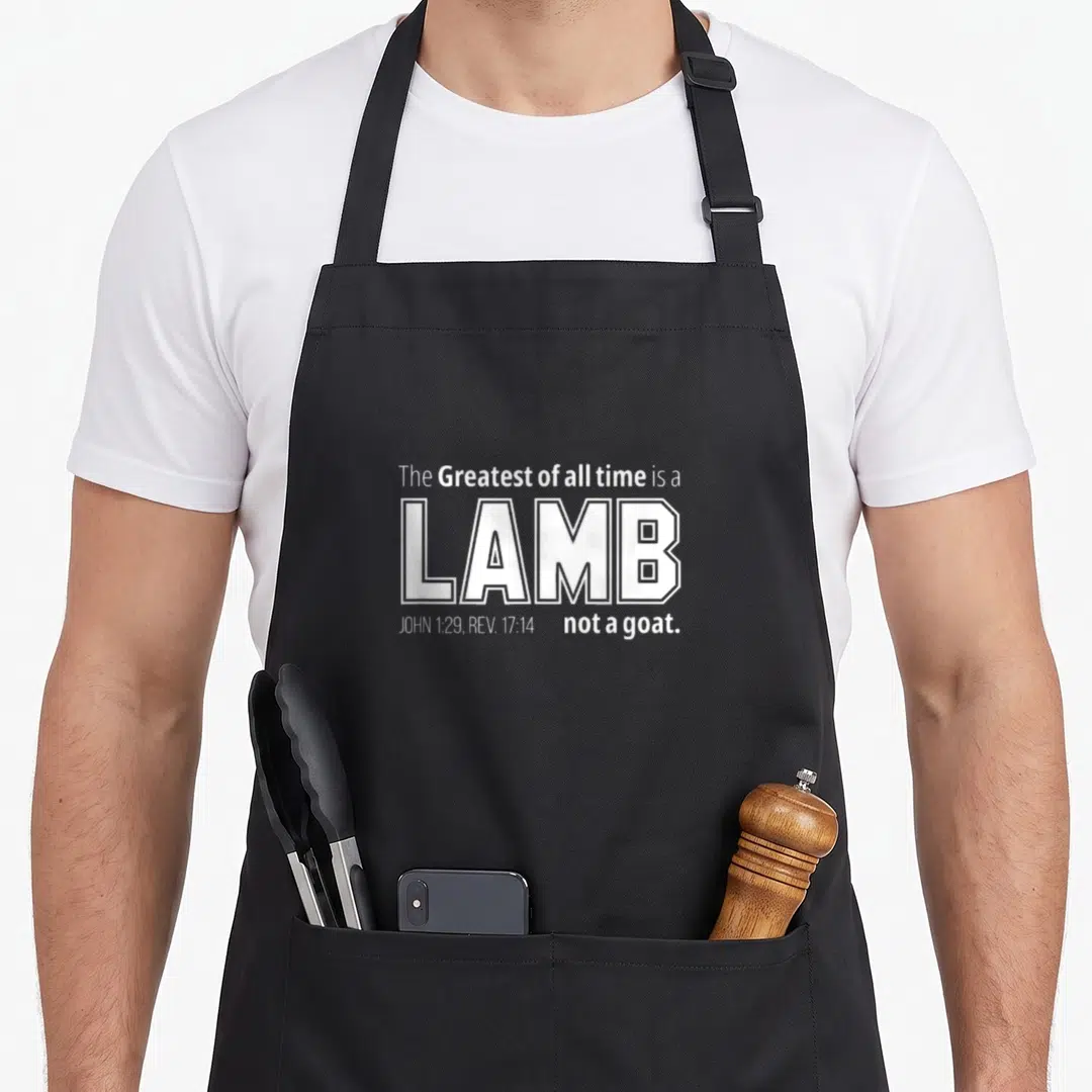 Lamb goat apron - White stacked text reading The Greatest of all time is a LAMB not a goat with scripture references — shown on a black cotton canvas apron against a white background