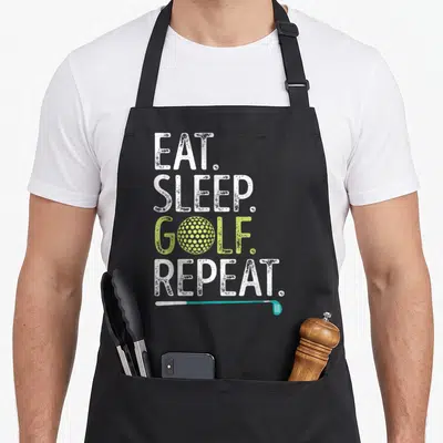 Eat golf apron - Stacked EAT SLEEP GOLF REPEAT text with lime ball and teal club — shown on a black cotton canvas apron against a white background