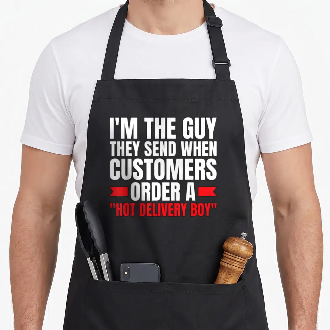 Driver food aprons - White stacked text I'M THE GUY THEY SEND WHEN CUSTOMERS ORDER A HOT DELIVERY BOY with red ribbon — shown on a black cotton canvas apron against a white background