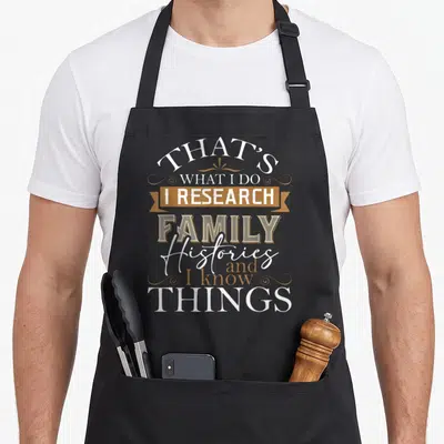 Research family aprons - Stacked white and tan typography reading THAT'S WHAT I DO I RESEARCH FAMILY Histories and I — shown on a black cotton canvas apron against a white background