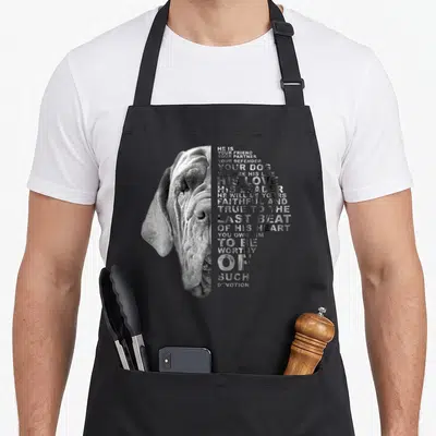 Partner dog apron - English Mastiff face photo beside stacked text about devotion and loyalty in grey and white — shown on a black cotton canvas apron against a white background