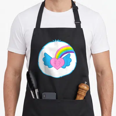 Dream halloween apron - Pink heart with blue wings and rainbow inside white fluffy circle — shown on a black cotton canvas apron against a white background
