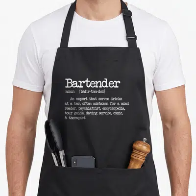 Definition bartender apron - White dictionary definition text listing bartender roles on a black background — shown on a black cotton canvas apron against a white background