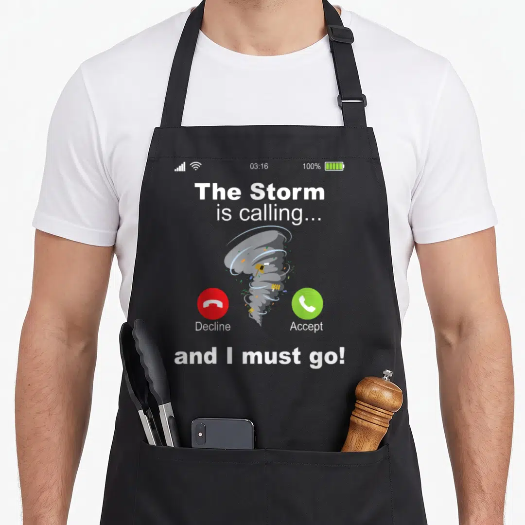 Calling storm chasing apron - Smartphone screen graphic with grey tornado, red decline button, green accept button — shown on a black cotton canvas apron against a white background