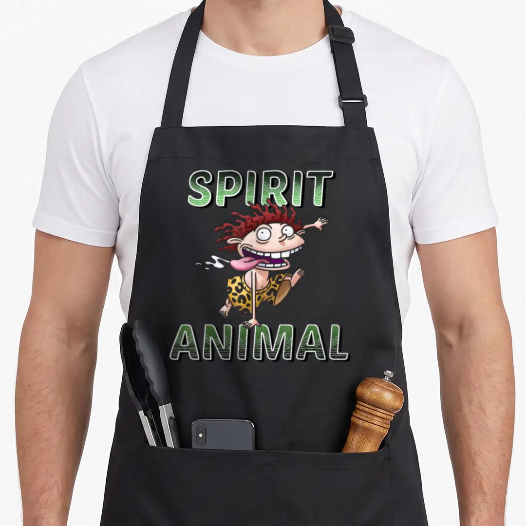 Thornberry animal apron - Cartoon man with red hair between green SPIRIT and ANIMAL text — shown on a black cotton canvas apron against a white background